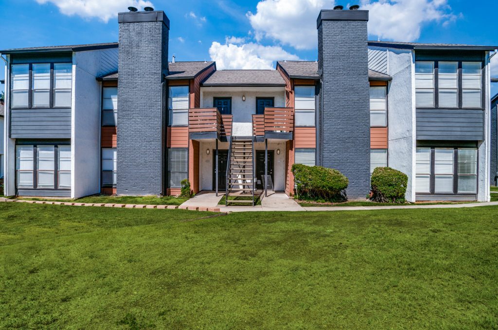 the exterior of an apartment complex with grass and trees at The Evaline